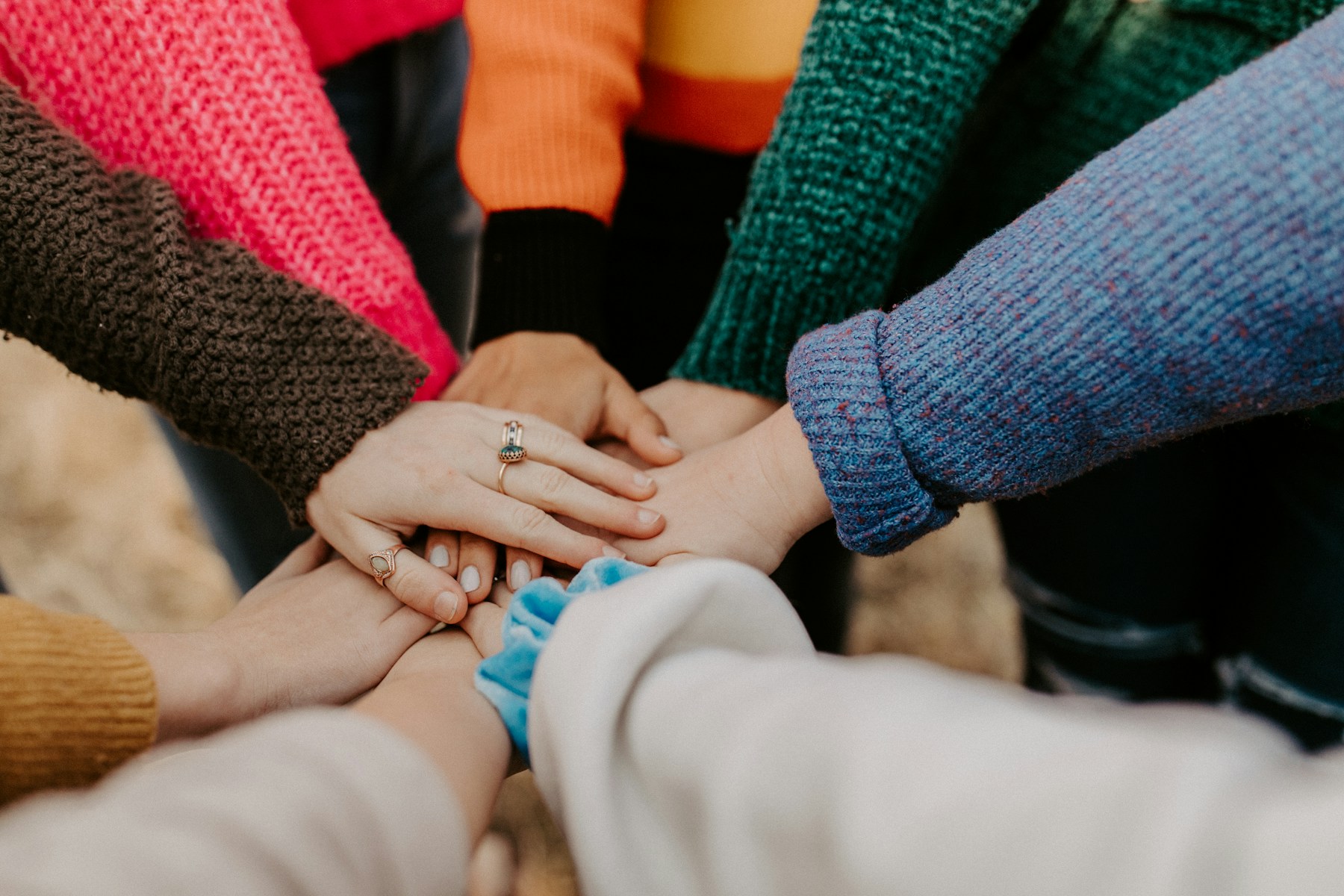 Hands stacked together in a gesture of community support.