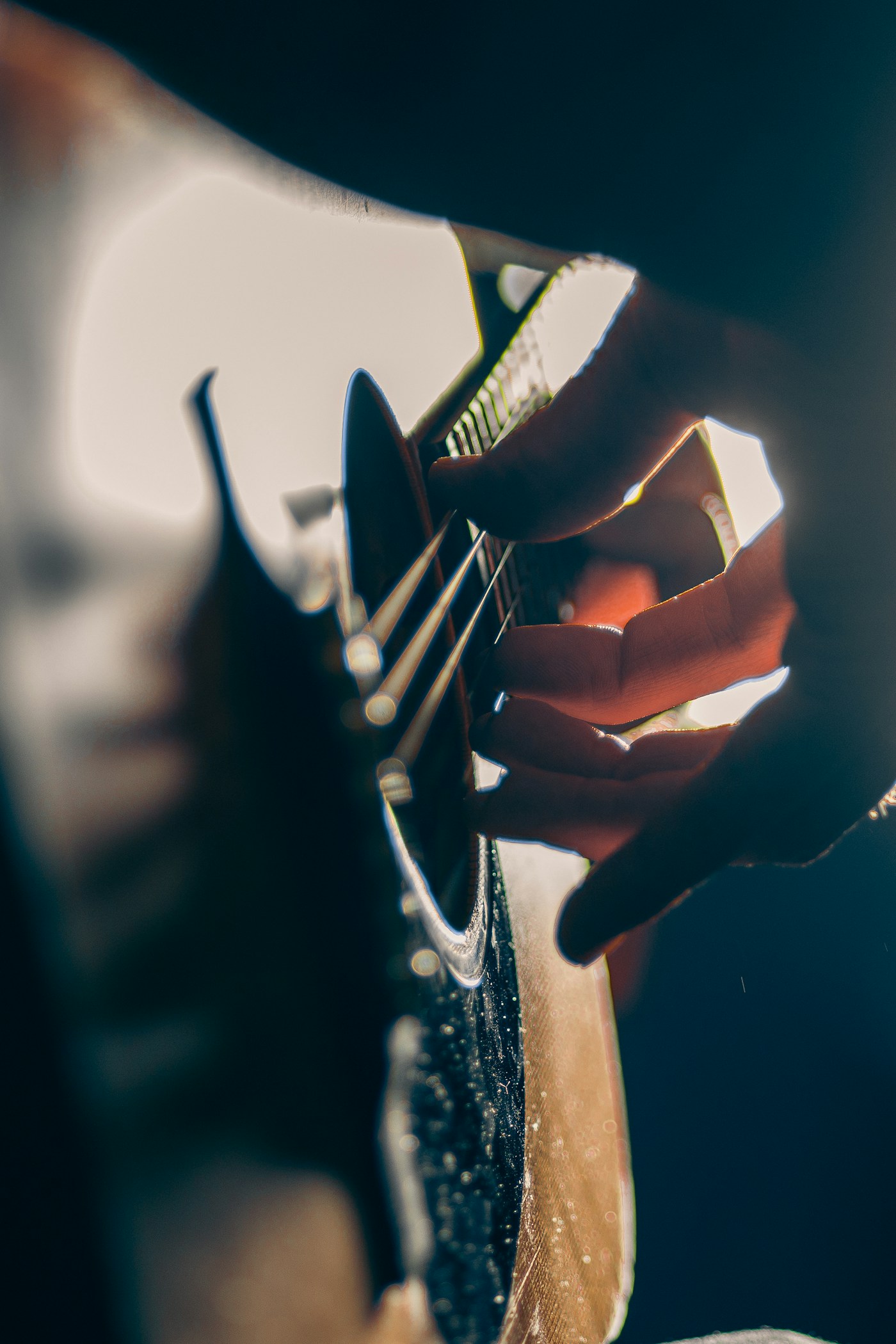Close-up of hands playing an acoustic guitar in warm light.
